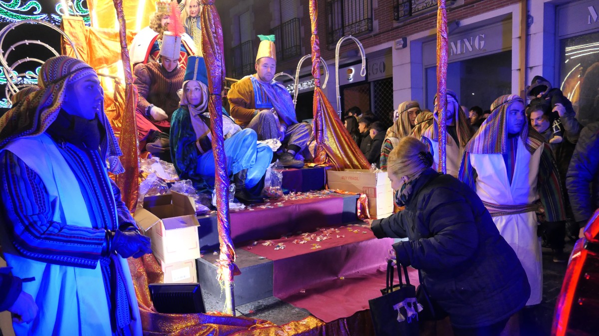Una mujer recoge caramelos de la carroza de Melchor en la Cabalgara de Reyes de Ávila.