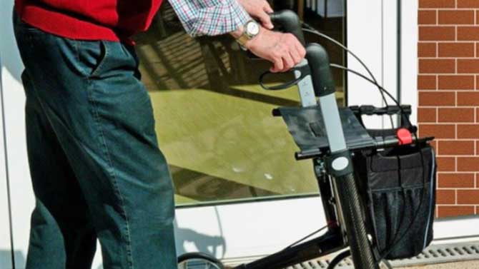 Una anciano pasea con un andador.