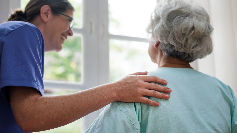 Una cuidadora atiende a una anciana.