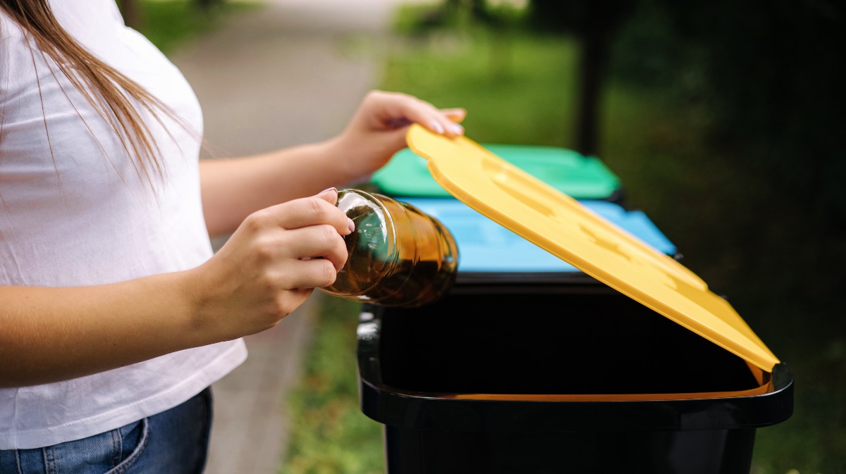 Imagen de archivo de una mujer ante depositando en un envase en un contenedor.