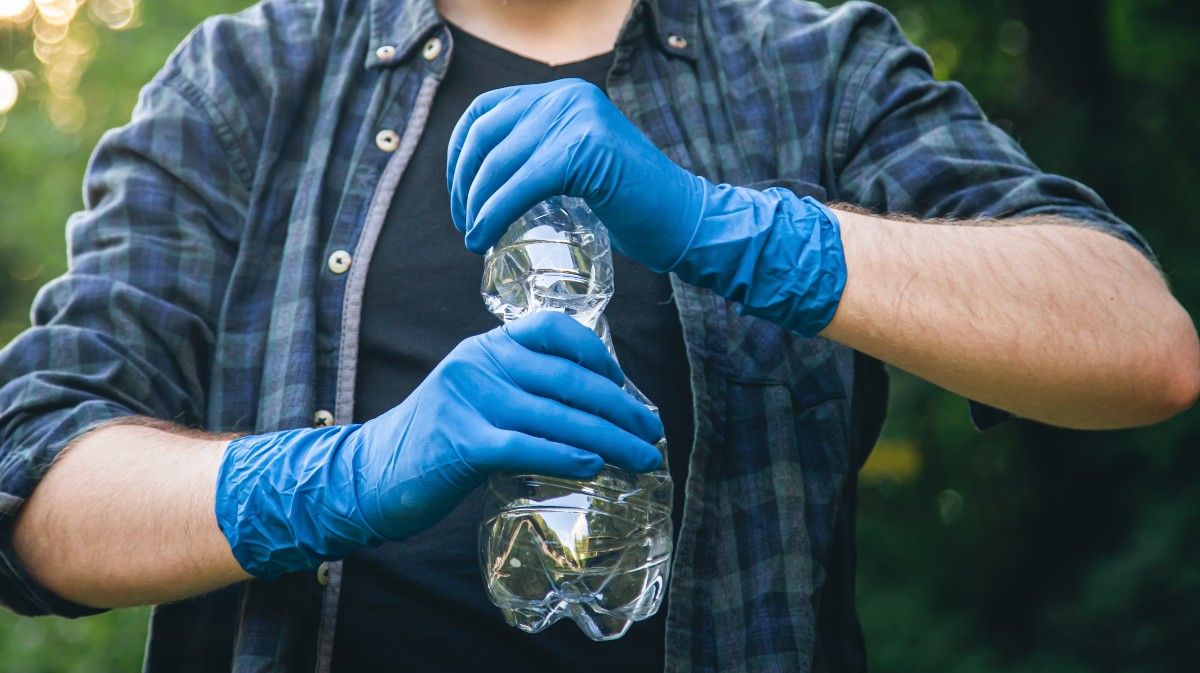 Un hombre recicla un plástico en el Punto Limpio.