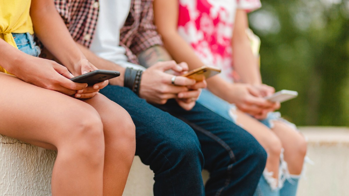 Varios j&oacute;venes consultan sus dispositivos m&oacute;viles.