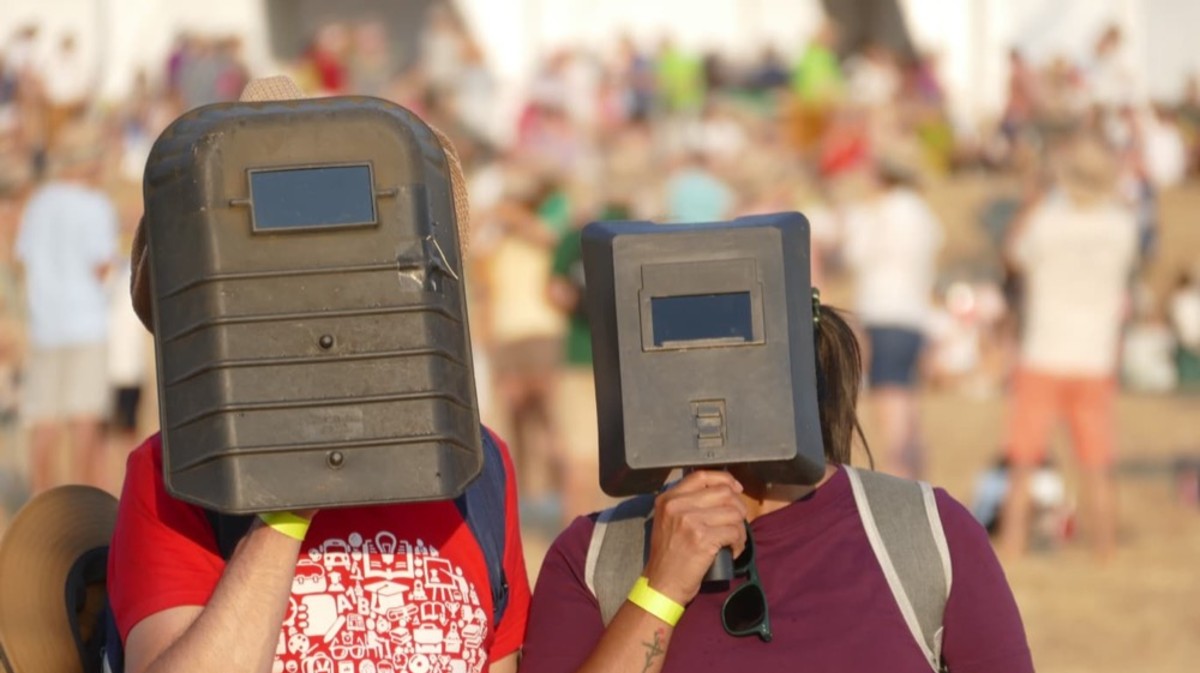 Dos personas bromean con gafas de soldador para avistar el eclipse.