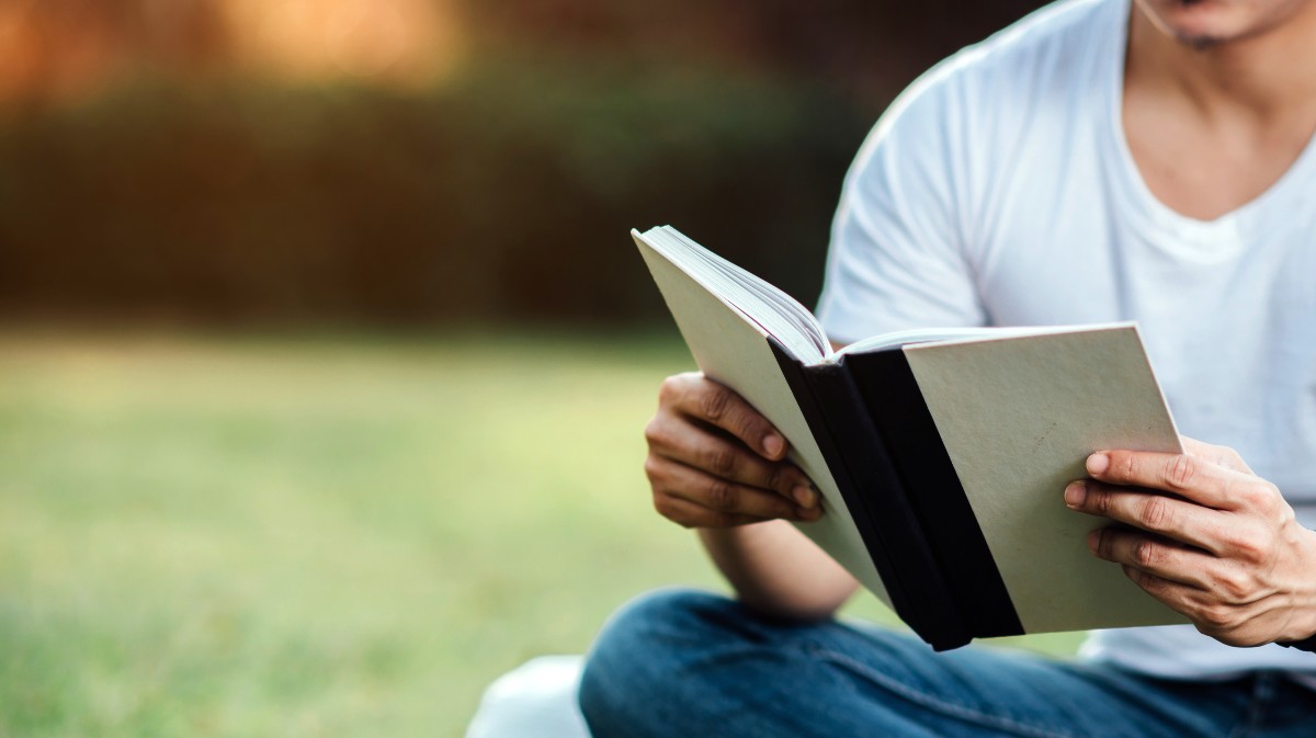 Imagen de archivo de un joven leyendo en un jardín.