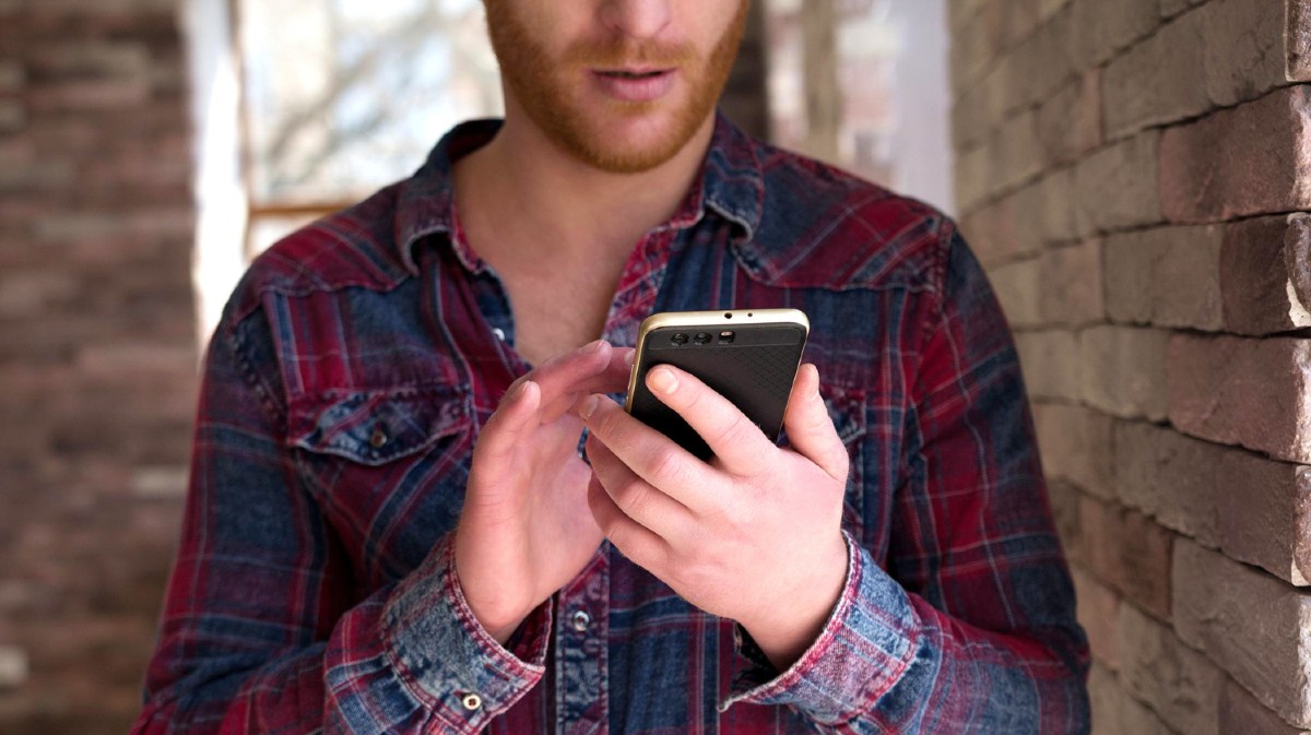 Un hombre maneja un tel&eacute;fono m&oacute;vil.