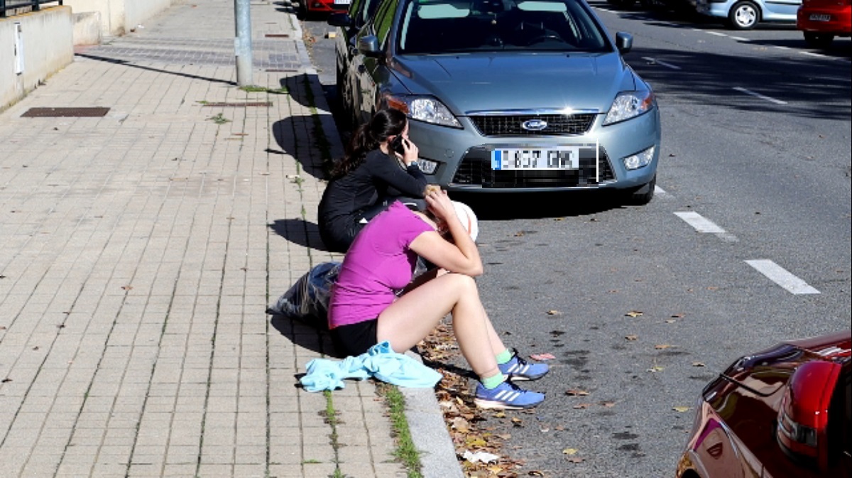 Dos opositoras a la Policía descansan junto a la Ciudad Deportiva tras realizar las pruebas físicas.