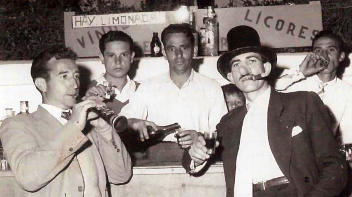 Generoso Santamaría (Langarica), a la derecha, fumando un puro y catando el morapio en el “Gran Bar” instalado en el barrio, 1958.