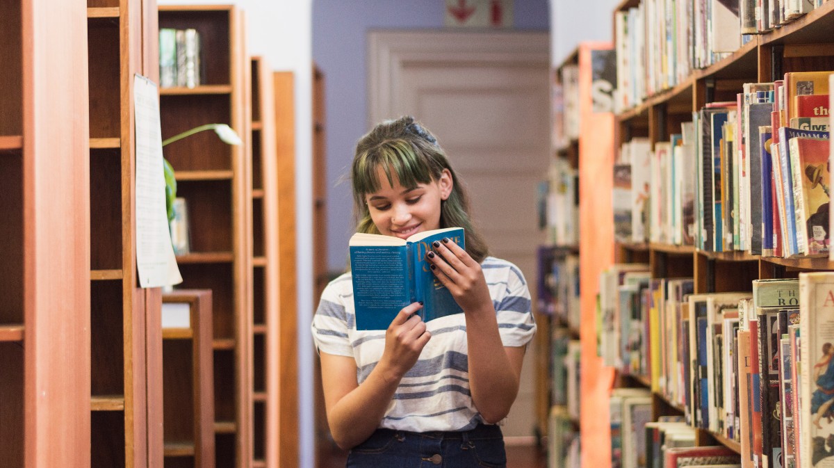 Una lectora lee en una biblioteca.
